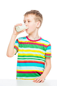 孩子从玻璃杯里喝牛奶，一个健康男孩概念的肖像