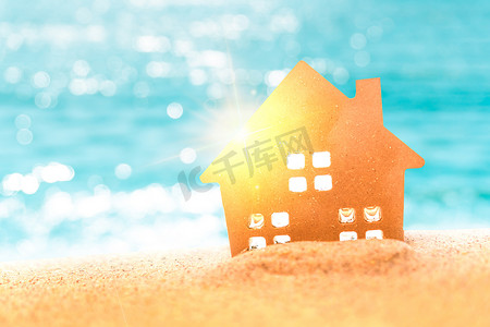 在阳光和海滩背景的沙滩上关闭微型家庭模型。