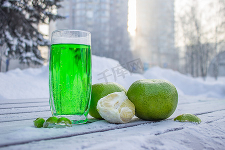 冬天水果摄影照片_冬天的早晨，玻璃杯中的新鲜果汁和柑橘类水果站在户外。