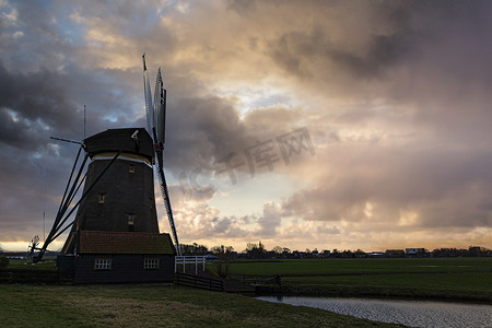 风车小屋摄影照片_荷兰风车迎着早雨风，运转涡轮机将水从土地中抽出