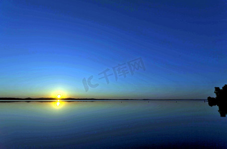 金色猪蹄子摄影照片_傍晚，金色的太阳落在湖面上