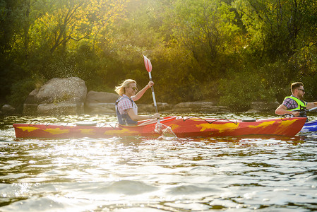 快乐的太阳摄影照片_年轻快乐的情侣在美丽的河流或湖泊上划皮划艇