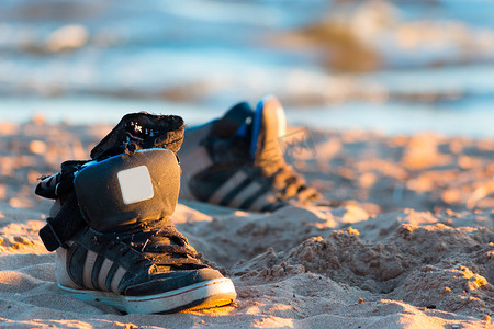 沙滩背景上带海浪的运动鞋