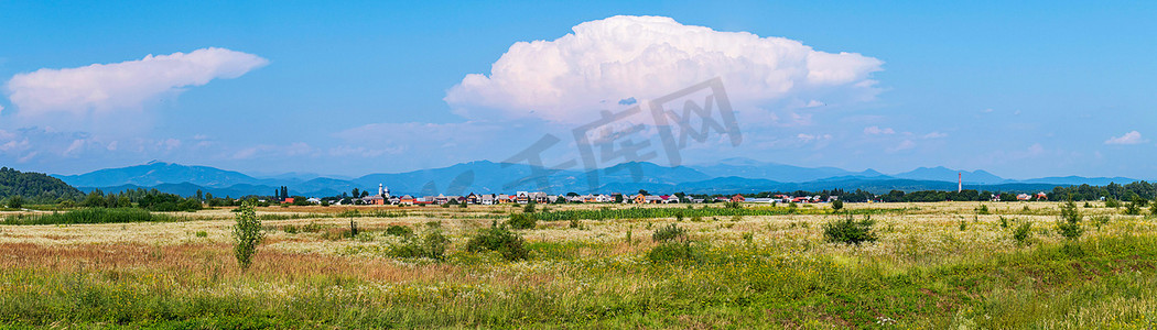 小山村摄影照片_一片巨大的白云映衬着蓝天，笼罩着一个小山村