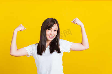 梦想实力摄影照片_年轻女子举起手臂二头肌，自信地展现力量和力量