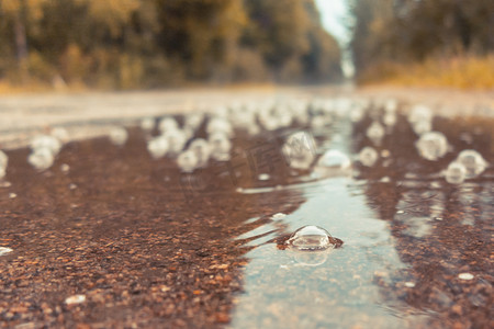 泡泡森林摄影照片_雨中路上的水坑里冒着泡泡。