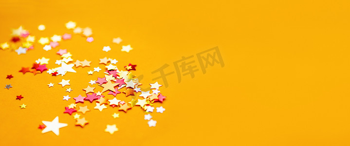 黄色假日背景与五颜六色的星形纸屑。