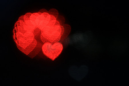 黑色背景上的红色心形彩色灯光散景装饰在夜间背景墙纸模糊情人节，爱情图片背景，灯光心形柔和在夜间摘要