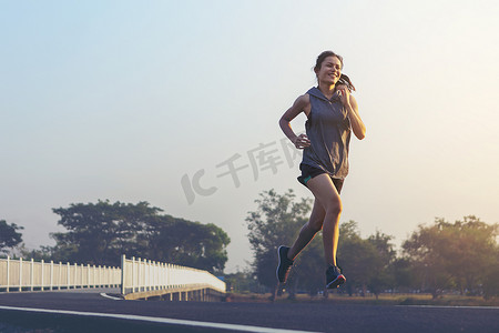 奔跑乌龟摄影照片_年轻女子赛跑者在路上奔跑。
