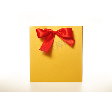 白色背景上带红丝带的黄色纸质礼品袋