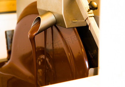 液体巧克力摄影照片_巧克力工厂中的液体巧克力搅拌器