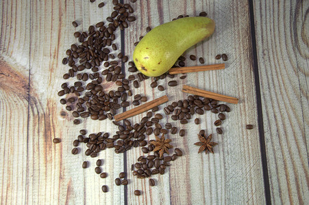 木桌上放着咖啡豆、肉桂棒、八角和成熟的梨。