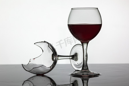 白酒红酒摄影照片_装满一杯红酒和碎红酒杯