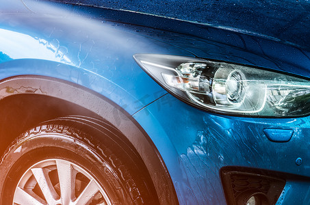 具有运动和现代设计的蓝色紧凑型 SUV 汽车正在用水清洗。