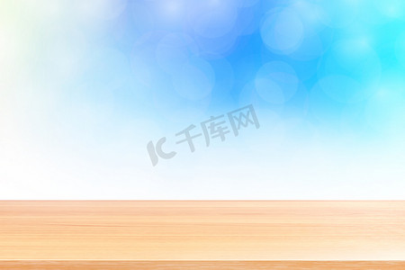 空木桌地板在模糊的散景柔和的蓝色白色渐变背景上，木板空在蓝色散景彩色光罩上，彩色散景灯渐变软，用于横幅广告产品