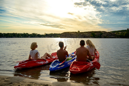 日落时，朋友们在美丽的河流或湖泊上划着皮划艇，在壮观的夜空下