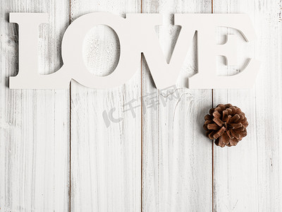 木制背景上的白色爱情文字和松果装饰