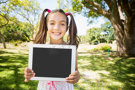 在公园里拿着数字平板电脑的年轻女孩