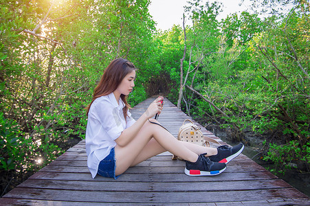 幻灭摄影照片_女孩独自坐在木桥上，手拿相机。