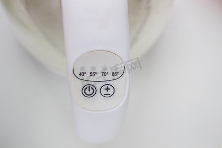 水壶上的按钮摄影照片_电热水壶上的电源和温度按钮是白色的。