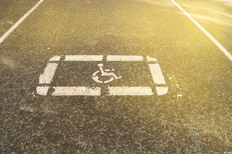 在空荡荡的停车场，阳光下，在沥青上涂上残疾人停车标志