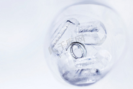 冻成冰块摄影照片_一对金色结婚戒指，镶嵌在冰块杯中的钻石。