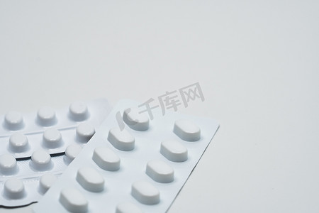 在白色背景上隔离的耐光包装的白色泡罩包装中片剂药丸的宏观拍摄细节。