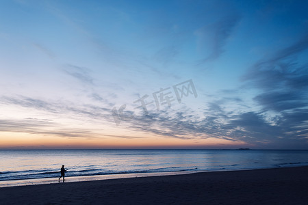 日落时沿着海边散步的人