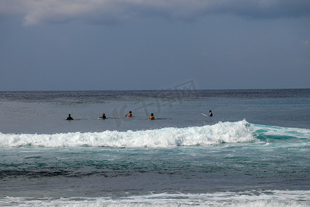 冲浪板上的身份不明的人在大海的后视中等待波浪。