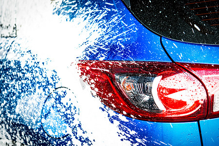 汽车广告设计摄影照片_蓝色紧凑型 SUV 汽车的后视图，带有运动和现代设计，用肥皂清洗。