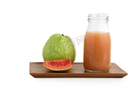 新鲜番石榴汁放在木杯垫上方的瓶玻璃上，上面放着生水果和切片水果