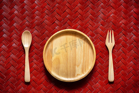 用勺子和叉子在编织竹子纹理上的空白木盘