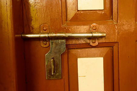 红色质感摄影照片_特写镜头前视图外部生锈粗糙旧棕色木门把手的铁金属框架与一个家庭客厅的全封闭门的低俗风格和良好的质感。