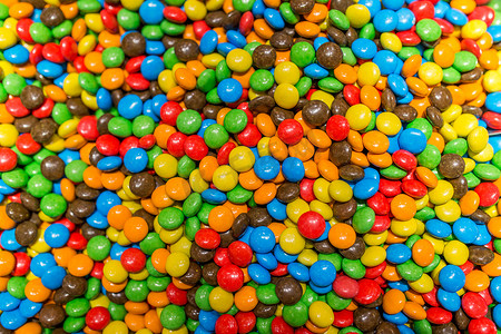 彩色糖果背景摄影照片_充满巧克力或耐嚼果冻的甜彩色糖果。