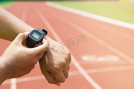 关闭手运动员检查他的手表比赛计时器跑步者准备在跑道上跑步。