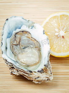 一半的价格摄影照片_木制背景上的柠檬新鲜牡蛎。