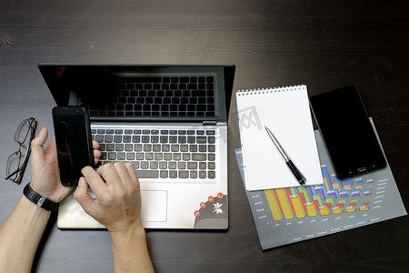 打印摄影照片_一个男人在笔记本电脑上打印，躺在手机旁边，平板电脑玻璃