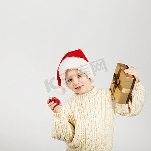 戴圣诞帽的男孩摄影照片_戴着圣诞帽的快乐快乐漂亮小男孩的画像