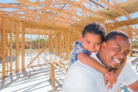 年轻的非洲裔美国父亲和混血儿儿子在他们的新住宅建筑框架内现场。