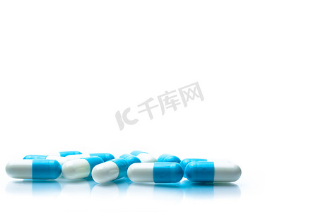 一堆蓝色和白色的胶囊药片在白色背景上被隔离，带有阴影和文本复制空间。
