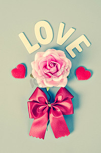 粉红蝴蝶结摄影照片_粉红玫瑰和带有红色蝴蝶结的情词。