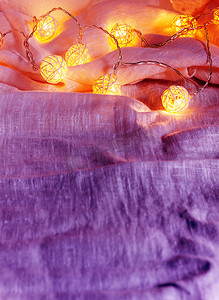 织物褶皱摄影照片_织物褶皱上带球灯的花环背景 i