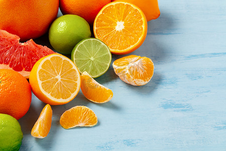 一组完整和切片的柑橘类水果 — 蓝桌表面的柑橘、柠檬、酸橙、橙子、葡萄柚 — 带有复制空间的图像