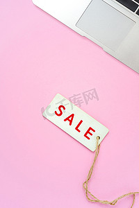 粉红色背景的销售标签和笔记本电脑，网上购物