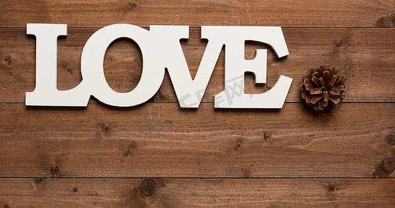 木制背景上的白色爱情文字和松果装饰