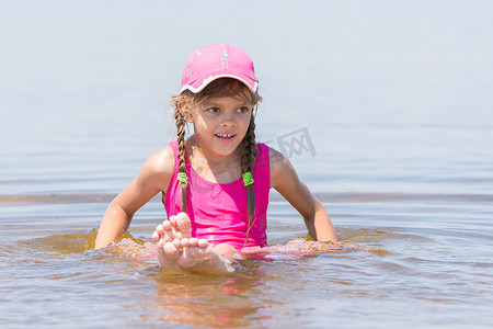 戴帽子的女孩坐在水中的浅河上