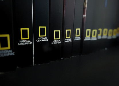 黑色书籍的书脊存放在带有国家地理标志的架子上