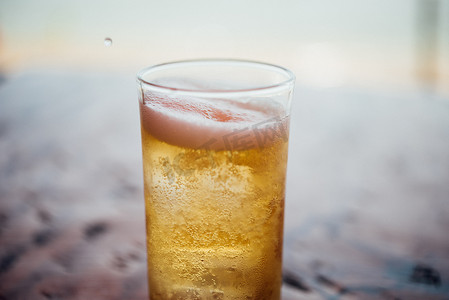 将新鲜啤酒水倒入加冰和泡沫的玻璃杯中