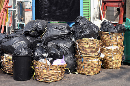 垃圾袋塑料袋摄影照片_垃圾堆成堆，人行道社区村有许多垃圾塑料袋黑色垃圾，垃圾塑料垃圾造成的污染，塑料垃圾袋箱，垃圾堆，垃圾堆