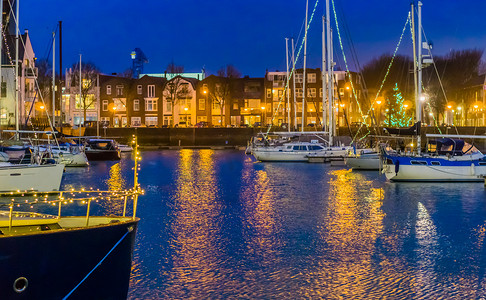 晚上的弗利辛根港，用灯光装饰的船只，用水点亮的城市建筑，荷兰泽兰的热门城市